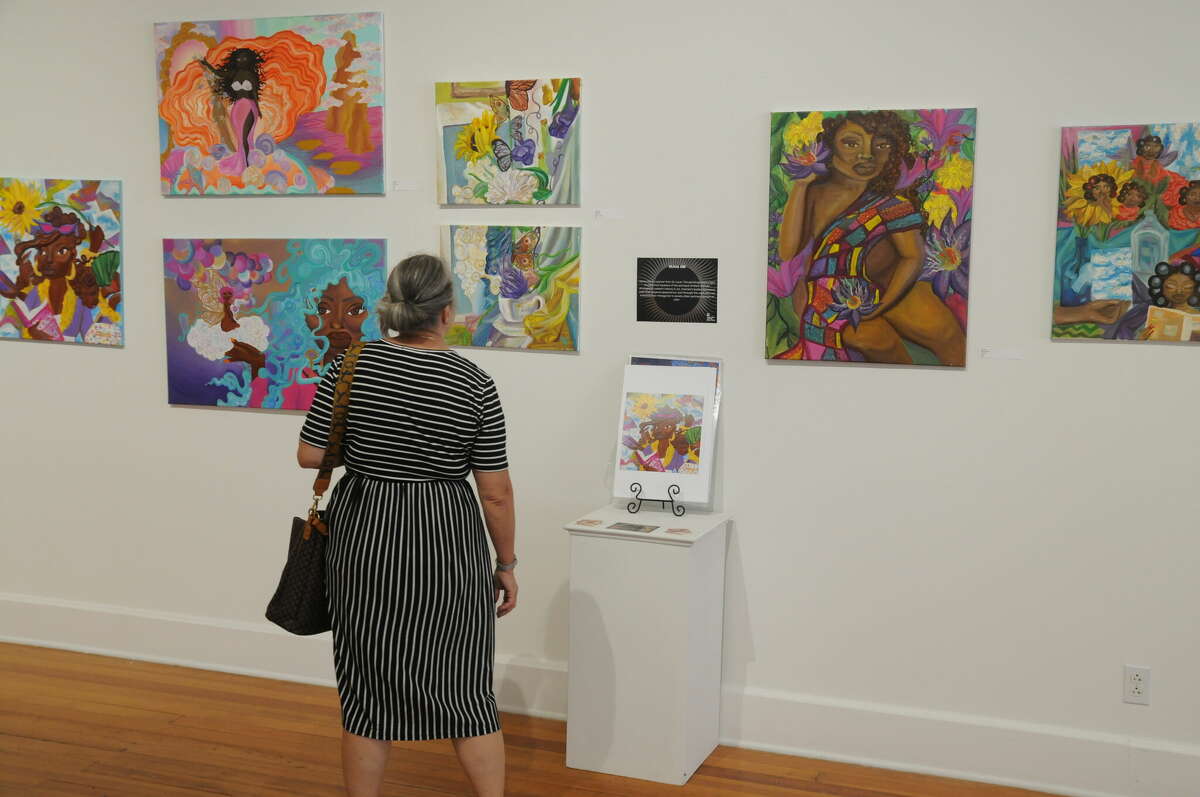Gallery guests examine an artist's works as part of the RISE: Artists of Color Showcase, a two-month exhibition that closed over the weekend at the Jacoby Arts Center.