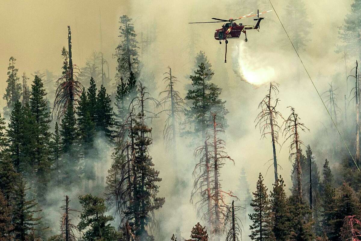 Гледано от некорпоративен окръг Марипоза, Калифорния, хеликоптер пуска вода върху горящия пожар Уошбърн в национален парк Йосемити, събота, 9 юли 2022 г.