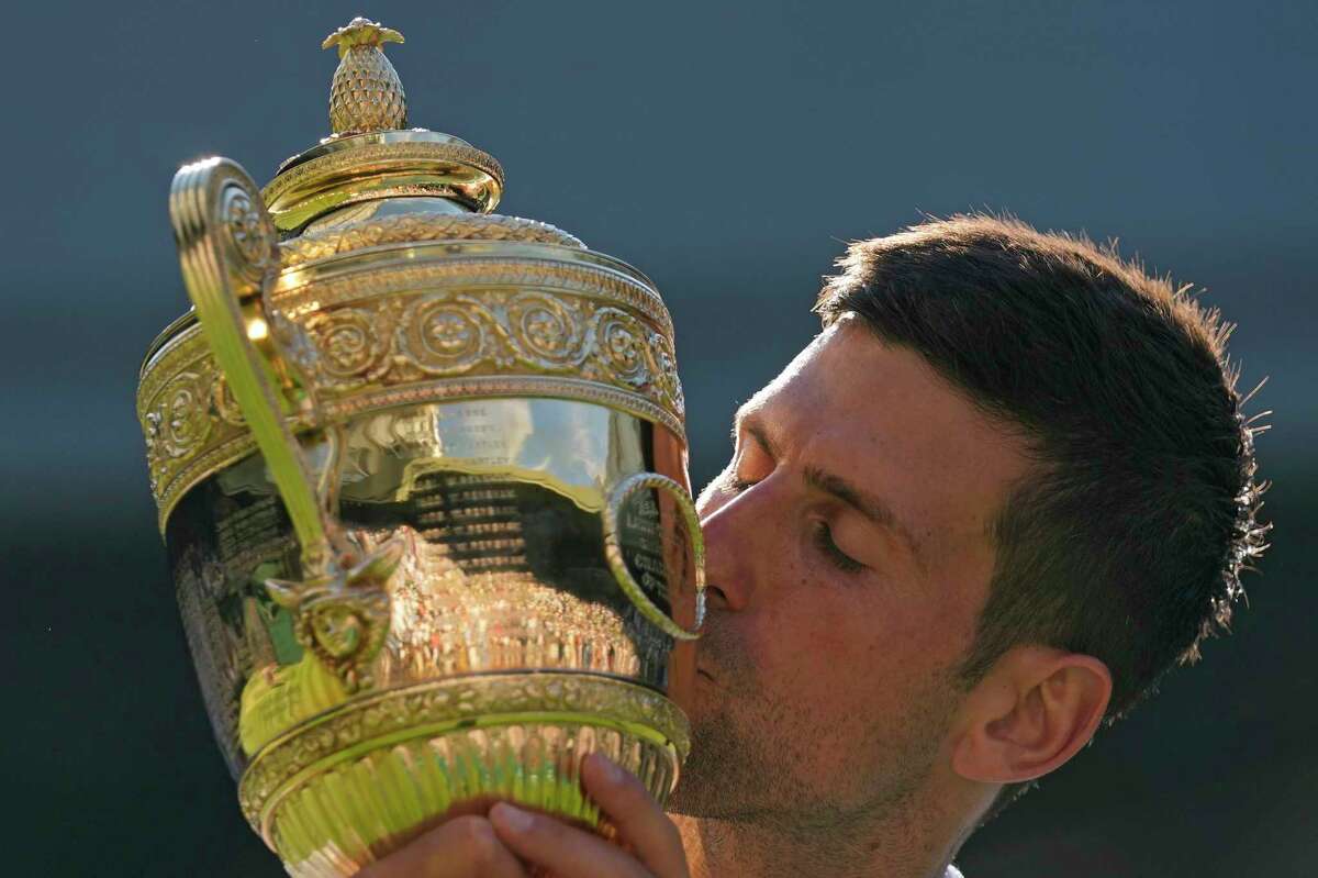 Serbia's Novak Djokovic kisses the trophy as he celebrates after beating Australia's Nick Kyrgios to win the final of the men's singles on day fourteen of the Wimbledon tennis championships in London, Sunday, July 10, 2022. (AP Photo/Alastair Grant)