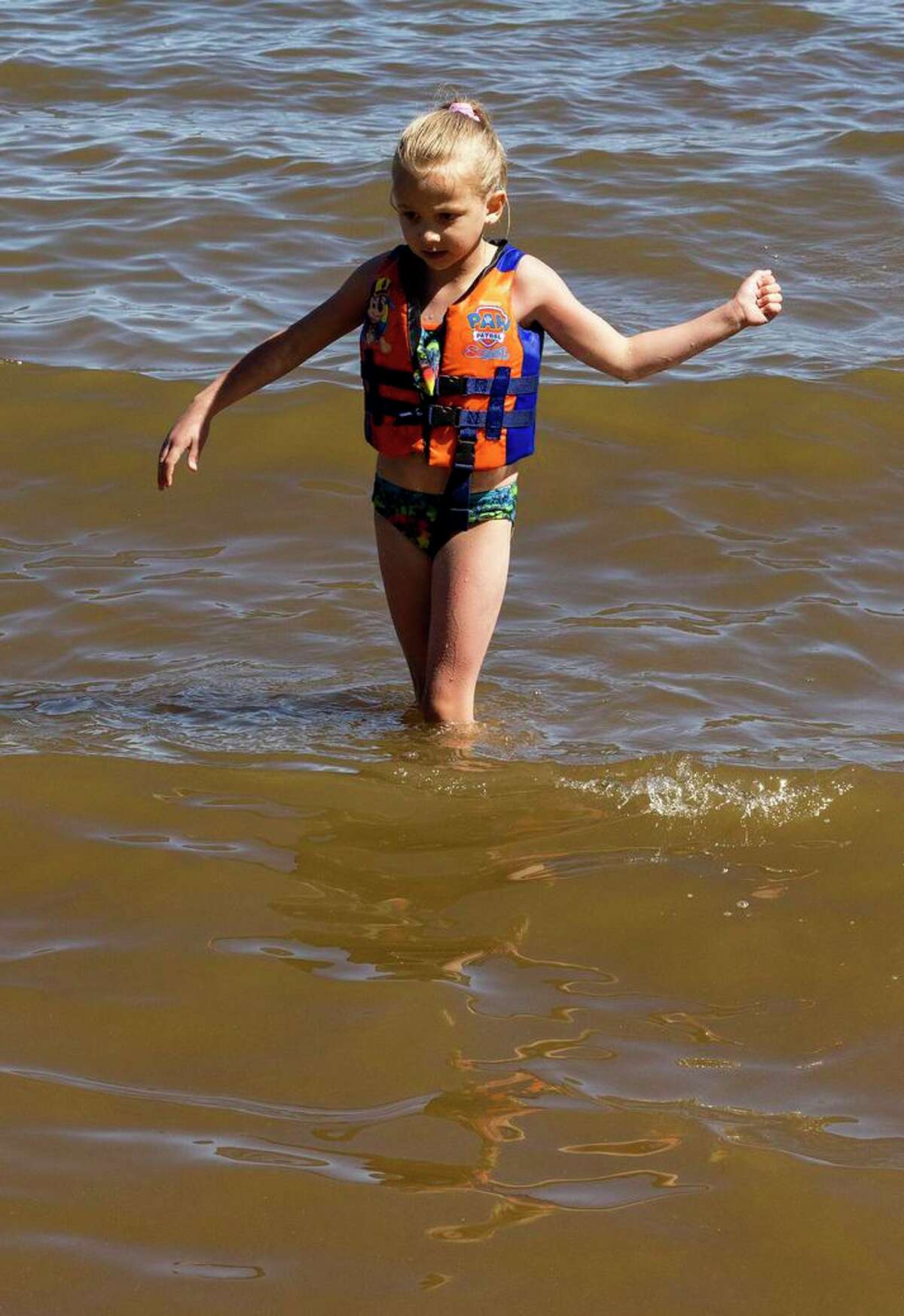 内华达州卡森市6岁的阿利亚·欧文斯(Aliyah Owens)周五，他涉水到南太浩湖埃尔多拉多海滩的多云水域。