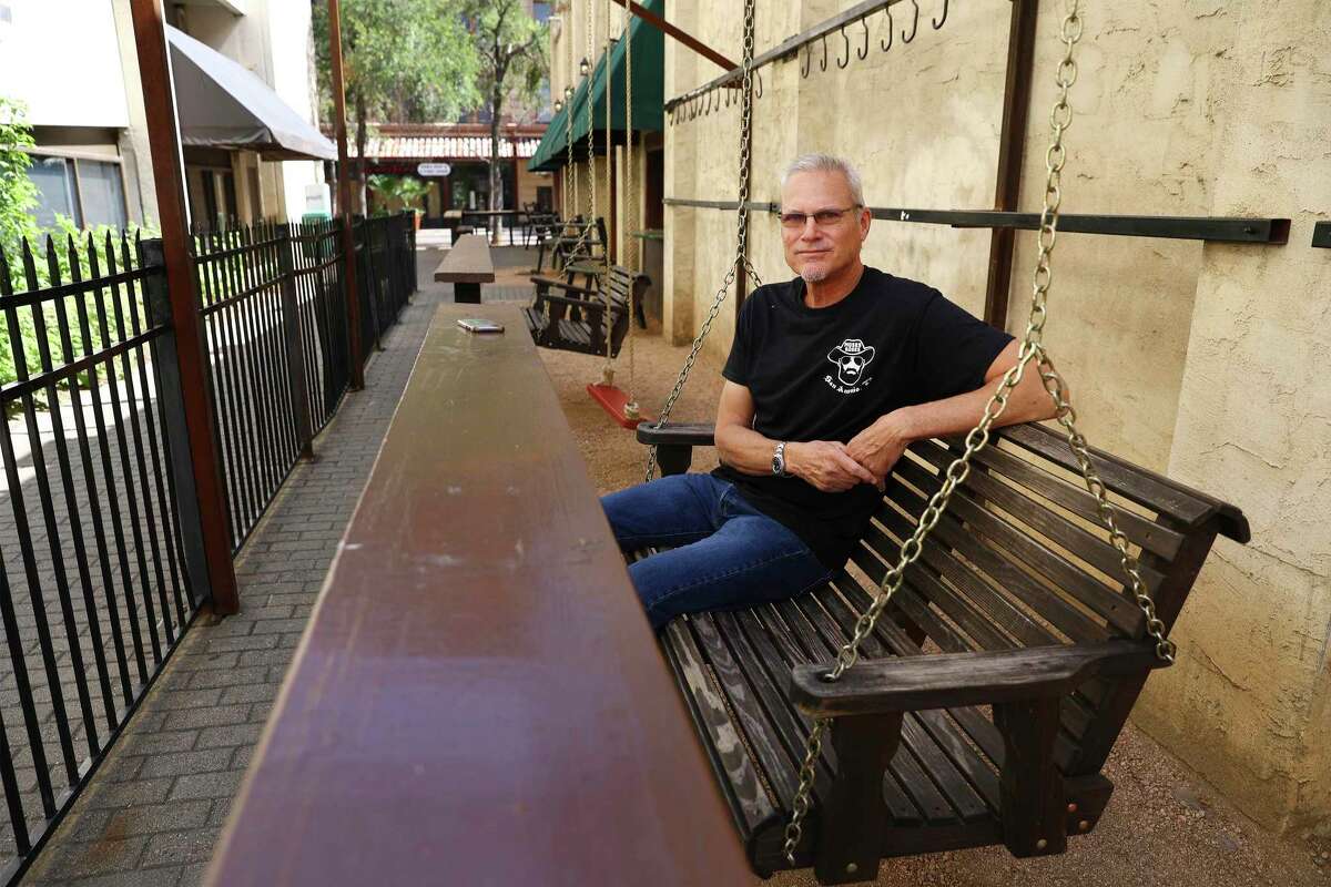 Moses Rose's Hideout bar owner Vince Cantu sits on a swing outside of his bar that is beside Maverick Walk on Thursday, July 7, 2022. One of the last business holdings in the footprint of the Alamo project, a bar ironically named after Louis “Moses” Rose, who is said to have fled the fort during the 1836 siege, has been given until July 11 to surrender its patio to the General Land Office for development of an Alamo museum and visitor center. Cantu's bar, Moses Rose’s Hideout, sits near the historic Woolworth Building on Houston street, and its patio is on city property, a right-of-way known as Maverick Walk, that is being leased to the GLO for the massive Alamo makeover. The bar’s sidewalk patio permit from the city expired more than two years ago. But Cantu says eliminating his outside patio area “may be the thing that puts me out of business” after surviving COVID, riots, cancelled conventions and high gas prices. He’s asking the Land Office to stand down until the end of the summer tourist season, noting that the amusement businesses fronting Alamo Plaza have until Oct. 31 to vacate.