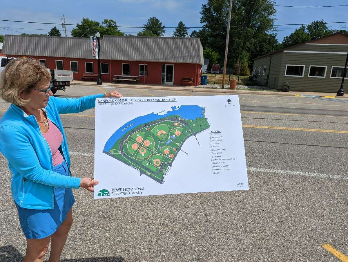 Sanford Village President Dolores Porte holds a layout of the new Village Park where work is underway. The park was destroyed during the May 2020 dam breach. Village officials hope to see it restored by June 2023.