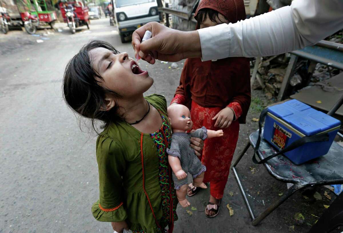 A health worker gives a polio vaccine to a girl on a street in Lahore, Pakistan, Monday, June 27, 2022. Pakistan launched a new anti-polio drive in June with the goal to vaccinate a million children across Pakistan.