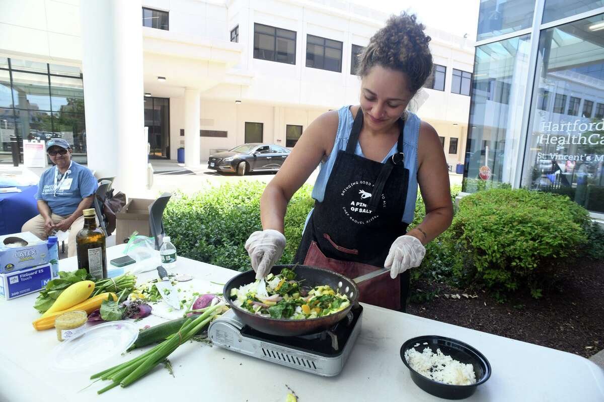 Chef Raquel Rivera prepares a stir fry using fresh vegetables during a cooking demonstration at the weekly Health and Wellness Farm Stand at St. Vincent’s Medical Center in Bridgeport, Conn. July 12, 2022.