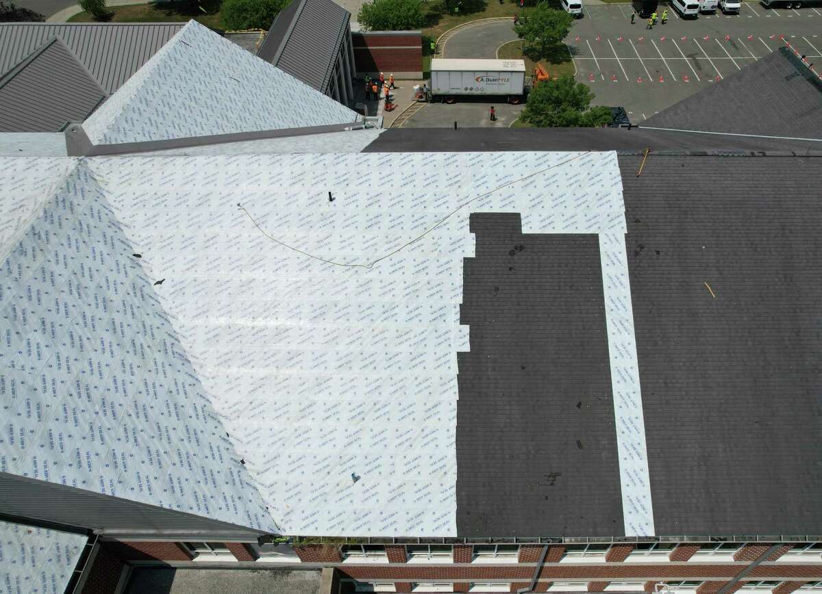 Repairs continue on the roof of New Milford High School in New Milford, Conn. Tuesday, July 12, 2022. The roof was badly damaged in a fire on July 5 and Mayor Pete Bass has isued a Declaration of Local Disaster Emergency that allows the town to expedite the process of repairing the roof.