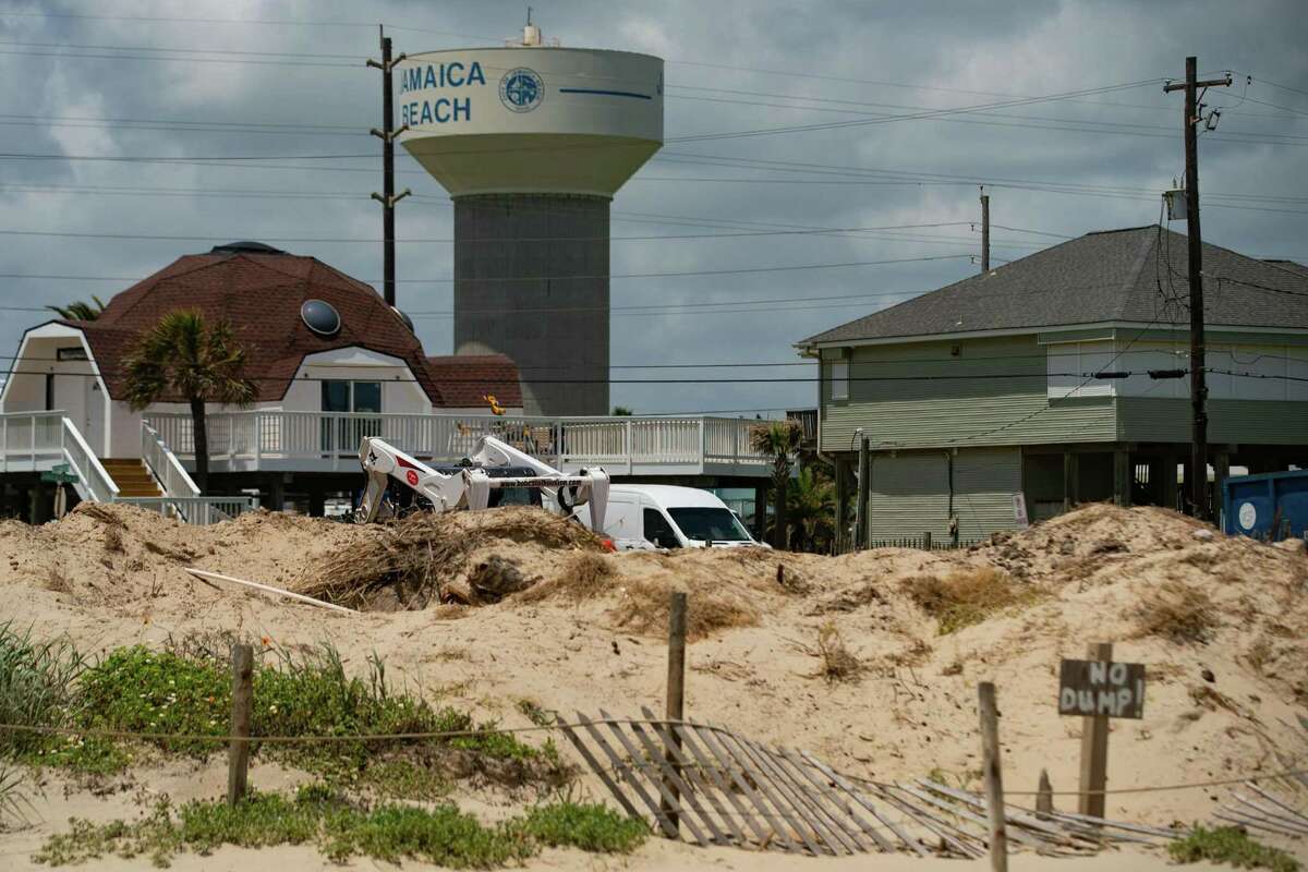 A small loader pushes sand towards an area where residents and city leaders are trying to build back dunes between the beach and their city, on May 11, 2022, in Jamaica Beach on Galveston Island.