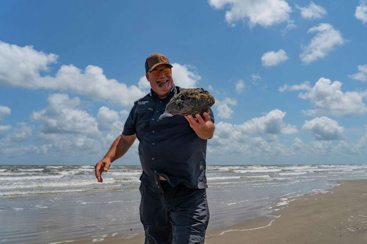 Jamaica Beach Mayor Clay Morris picks up a coconut along the beach, on May 11, 2022, in Jamaica Beach on Galveston Island.