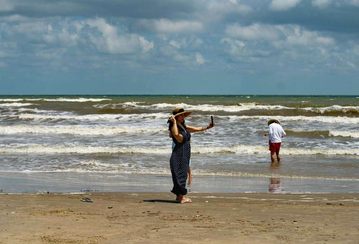 A woman takes pictures on the beach, on May 11, 2022, in Jamaica Beach on Galveston Island.