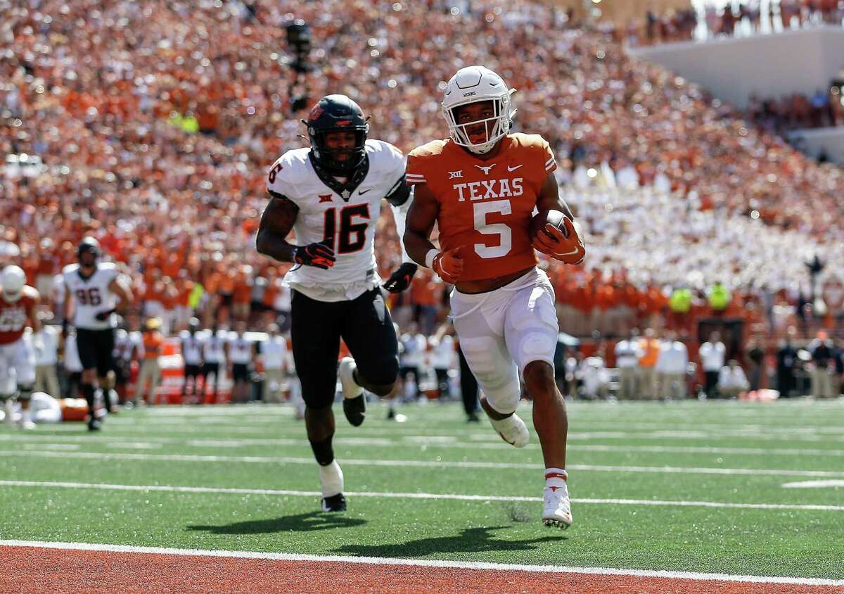 Bijan Robinson #5 of the Texas Longhorns catches a pass and runs for a touchdown while pursued by Devin Harper #16 of the Oklahoma State Cowboys in the second quarter at Darrell K Royal-Texas Memorial Stadium on October 16, 2021 in Austin, Texas.