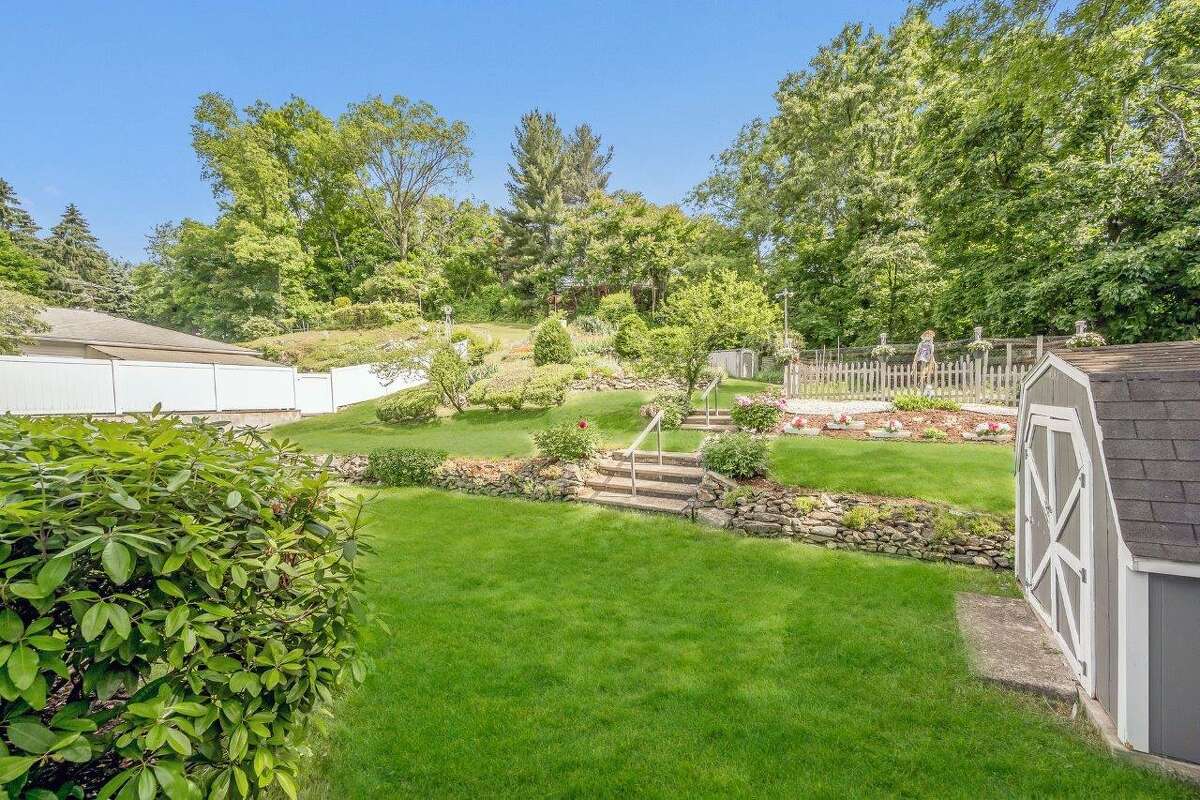 The three-bedroom home is sited on a 0.42-acre lot, with a deck, storage shed, lush lawn and tiered perennial gardens.   