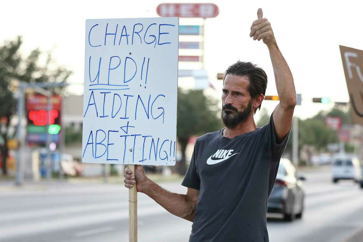 Uvalde resident Joe Canales gives a thumbs-up to a passing motorist as he holds a sign criticizing local police outside the Civic Center where the Uvalde City Council met on Tuesday.