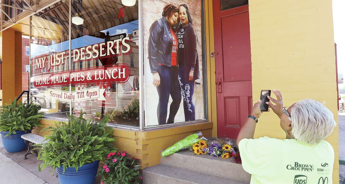 John Badman|The Telegraph A woman stops to take a picture of the life-sized picture of Yvonne Campbell, right, and her sister in a window at My Just Desserts in Alton following the news of Campbell's death Wednesday.