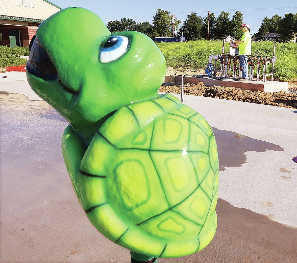 John Badman|The Telegraph A turtle shaped water sprayer sits ready for testing as a worker mans the valves that control the splash pad under development in Godfrey.