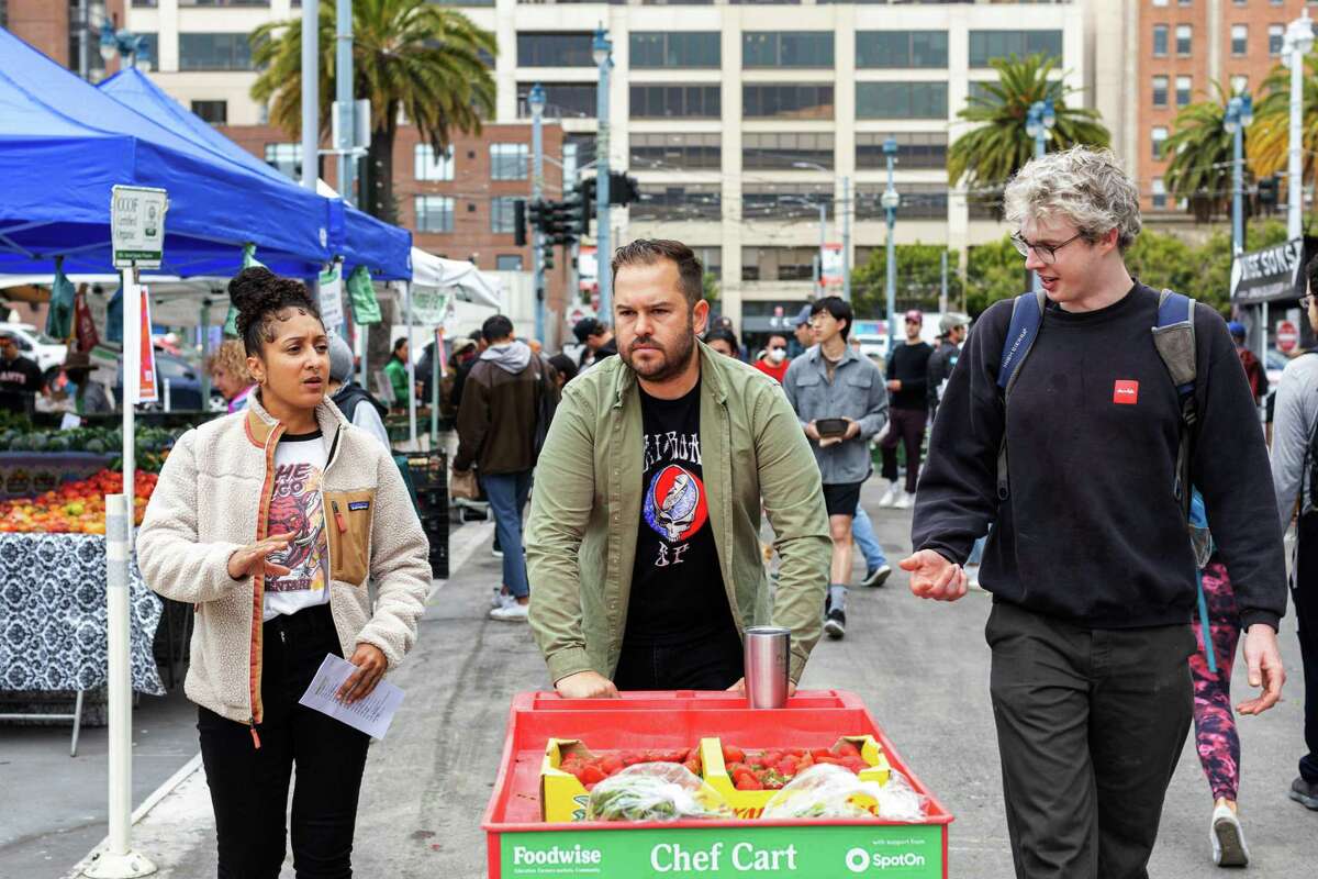 Che Fico executive sous chef Jazmine Fenton, left, walks through the Ferry Plaza Farmers Market in San Francisco with chef de cuisine Evan Allumbaugh, center, and line cook Matt Tillquist. She said working at Che Fico and going to the farmers market helped restore her love of cooking after working in toxic kitchens.