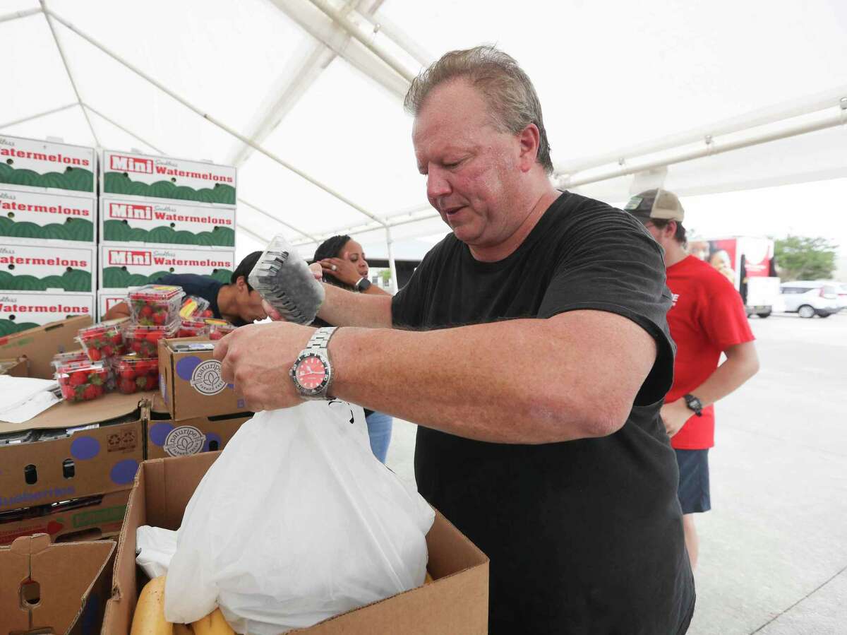 Eli Thomassan help bag fruit as he and other volunteers distribute 125 meals during a mobile food market from the Montgomery County Food Bank, Wednesday, July 13, 2022, in Conroe.