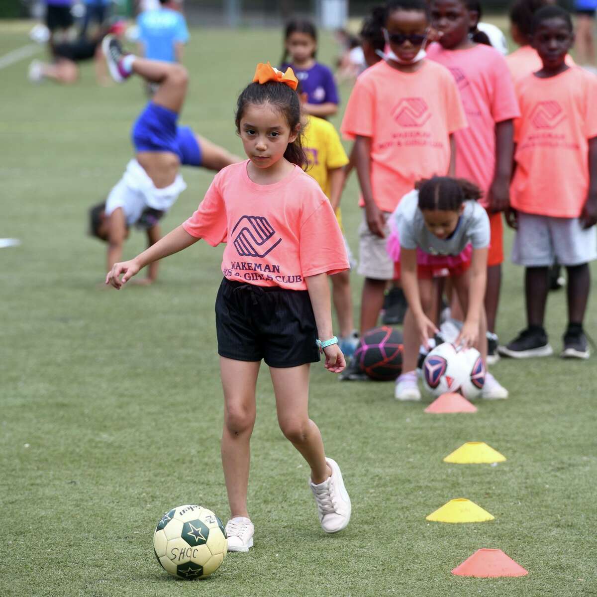 A girl dribbles a soccer ball during a health, wellness and soccer day camp at Wakeman Boys & Girls Club, in Fairfield, Conn. July 14, 2022.