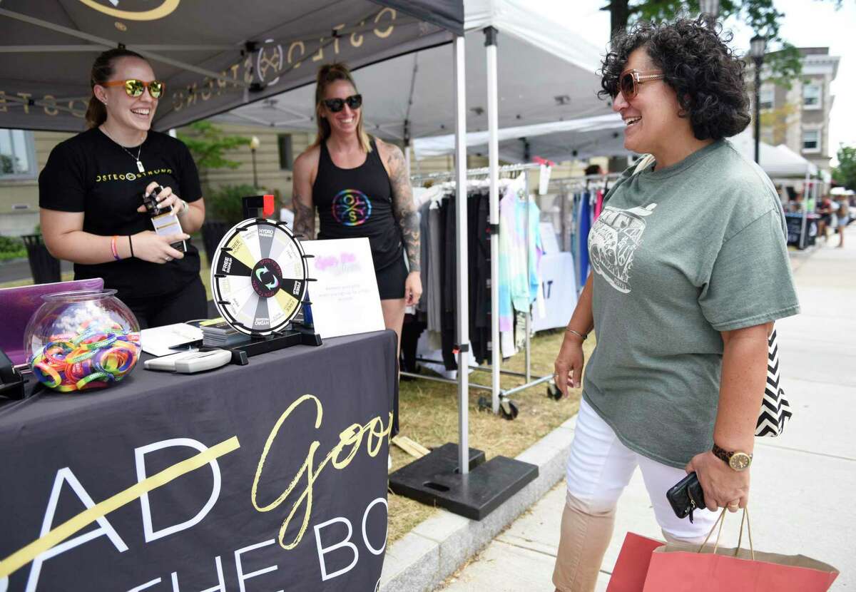 Stamford's Ellen DeSanctis, right, spins a giveaway wheel at the Osteo Strong booth during the 2022 Sidewalk Sales in Greenwich, Conn. Thursday, July 14, 2022. Presented by the Greenwich Chamber of Commerce, dozens of businesses participated in the sale by displaying their goods on the sidewalk at heavily marked-down prices. The sales continue from 9 a.m. to 7 p.m. Friday and Saturday and from 9 a.m. to 5 p.m. Sunday.