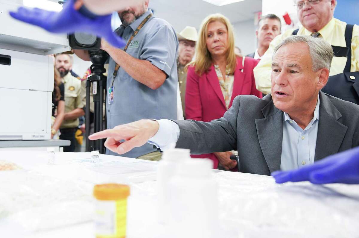 Texas Gov. Greg Abbott asks questions as DPS Seized Drug System Trainer Jennifer Hatch points out drugs laced with fentanyl during a tour of the facility with on Thursday, July 14, 2022 in Houston.