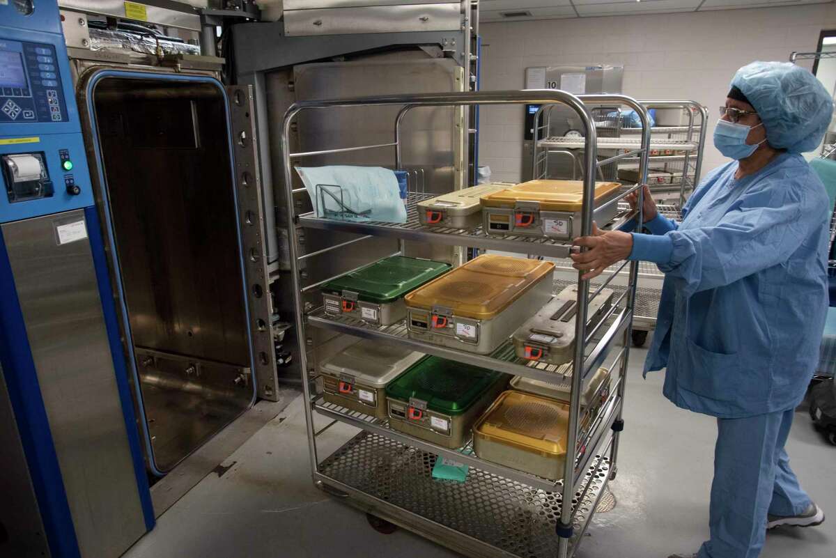 Naseem Khan, a sterile processing technician at Ellis Hospital, rolls a cart containing operating room instruments inside rigid containers into a sterilizer machine that uses steam generated from natural gas, on Thursday, July 14, 2022, in Schenectady, N.Y. (Paul Buckowski/Times Union)