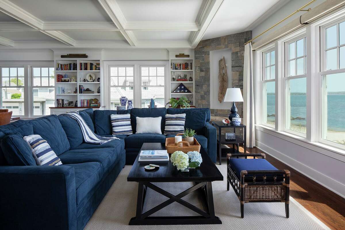 Aside from a deep ocean blue sectional, the living room utilizes light, neutral colors, as well as natural materials including a piece of driftwood mounted in a recessed corner stone wall, to flow with the coastal environs.