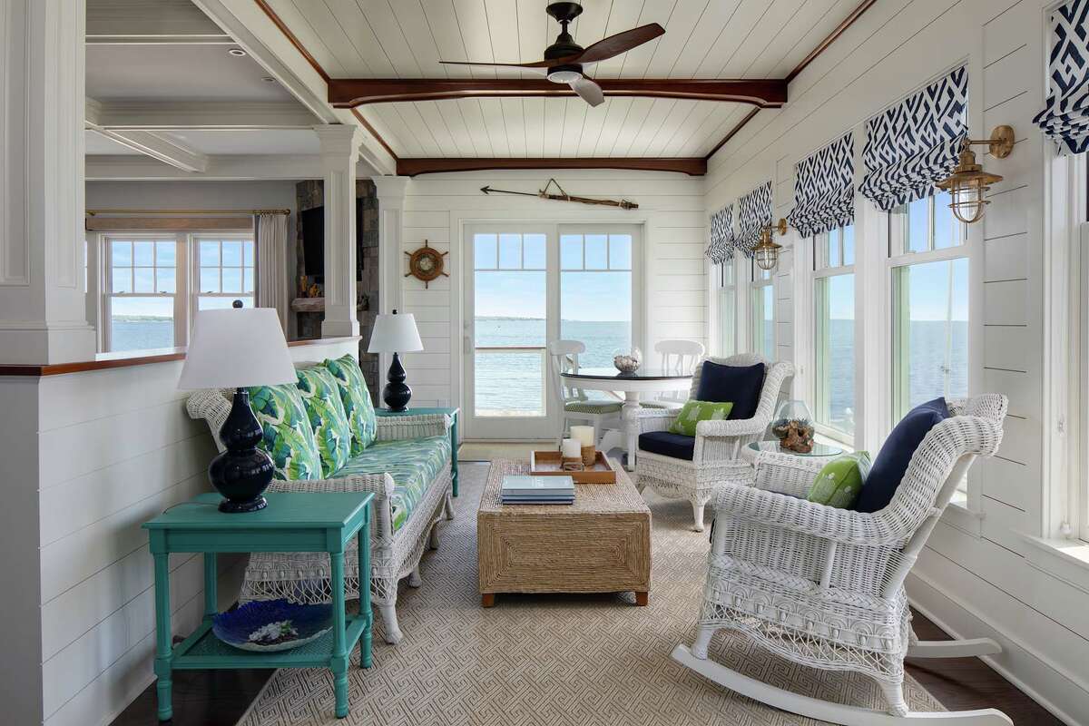 A half-wall separates the living room from the sunroom, which evokes the feeling of a boat with shiplap and a mahogany-arch ceiling design.