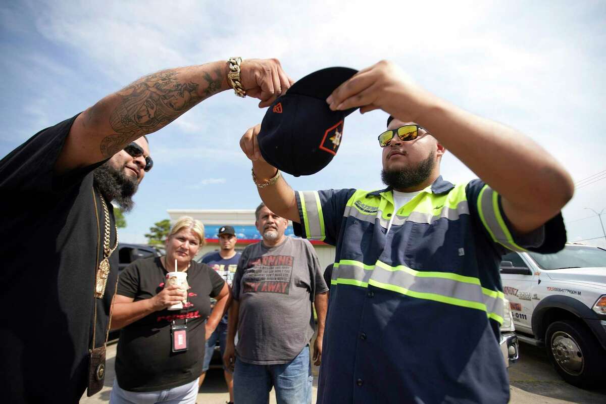 David Garcia reaches into a hat held by Anthony Hernandez, the hat is filled with chips that are county issued to the tow truck unit number, which used to be used as a lottery when responding to calls, as he and other tow truck drivers waited for a call on Wednesday, July 13, 2022 in Houston. The cost of getting towed in Harris County could be going up, with a new pilot program in effect in Precinct 2 after county commissioners approved an agreement with an Uber-like towing app last year. Some tow truck operators oppose the new $27.50 fee drivers must pay, arguing there is a less expensive alternative, while the sheriff's office says contracting with the towing app they selected will increase safety and efficiency.