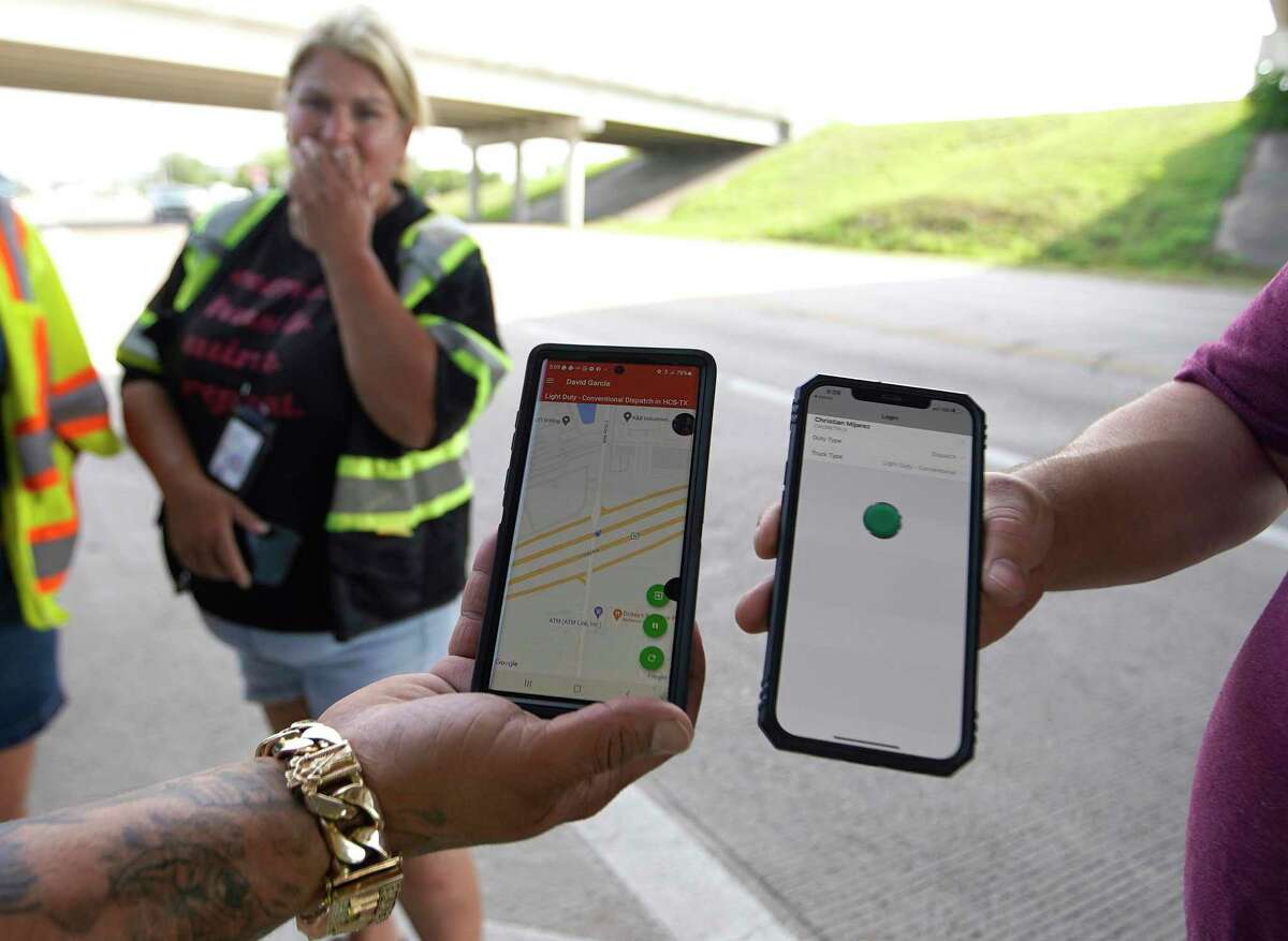 Tow truck drivers compare their Auto Return Apps as they waited for a call, in the shade under the freeway on Wednesday, July 13, 2022 in Houston. The cost of getting towed in Harris County could be going up, with a new pilot program in effect in Precinct 2 after county commissioners approved an agreement with an Uber-like towing app last year. Some tow truck operators oppose the new $27.50 fee drivers must pay, arguing there is a less expensive alternative, while the sheriff's office says contracting with the towing app they selected will increase safety and efficiency.