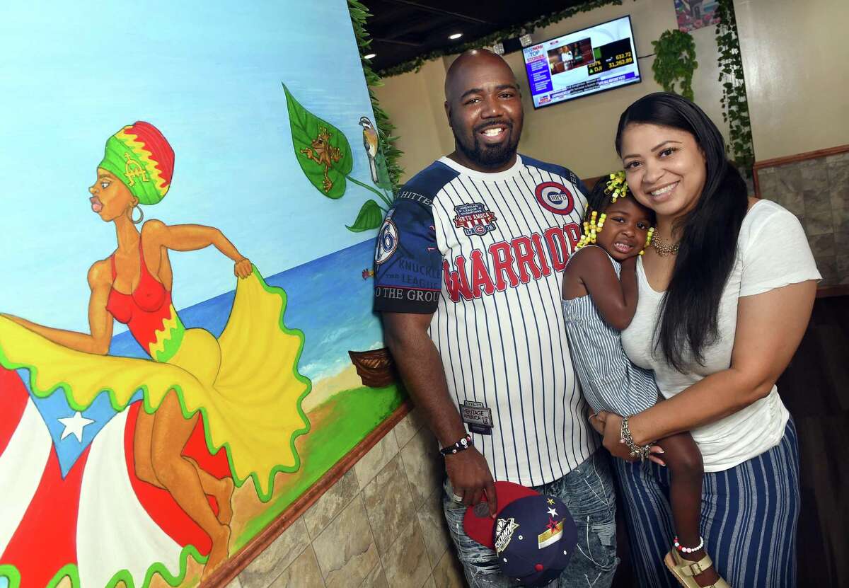 La Isla co-owners Darcus Henry, left, and his wife, Leli, are photographed at their new restaurant on Dixwell Avenue in Hamden with their daughter, Leila, 2.