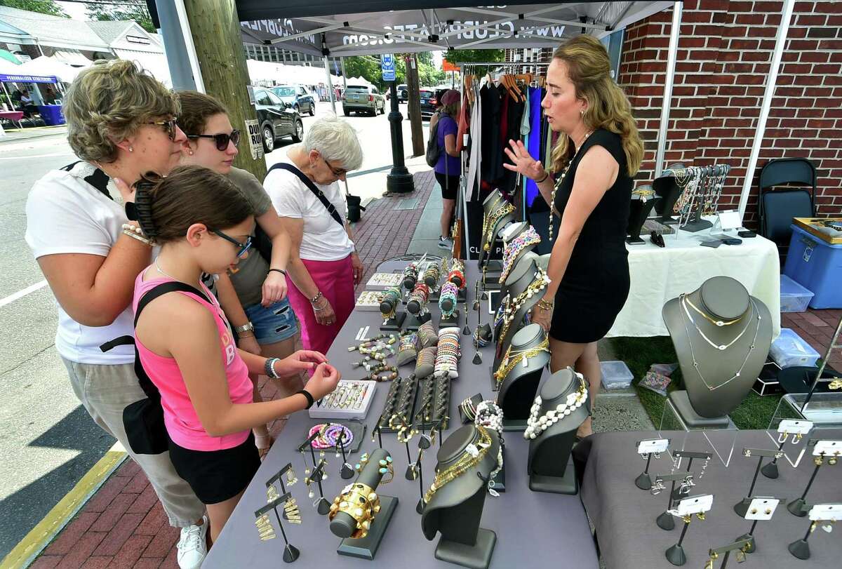 Benan Cakar, who ows Chakarr jewelry talks to shoppers at her stand during the Darien Chamber of Commerce’s Darien Sidewalk Sales event for businesses up and down Post Road in Darien, Conn., on Friday July 15, 2022. The sidewalk sales will also run from July 16, 10 a.m. to 5 p.m.