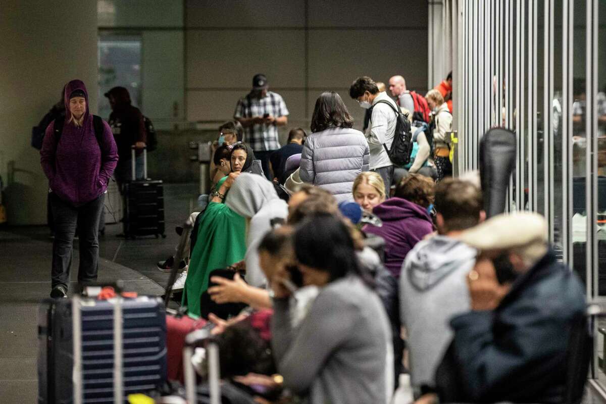 Travelers wait outside the international arrival terminal after a bomb threat at San Francisco International Airport.