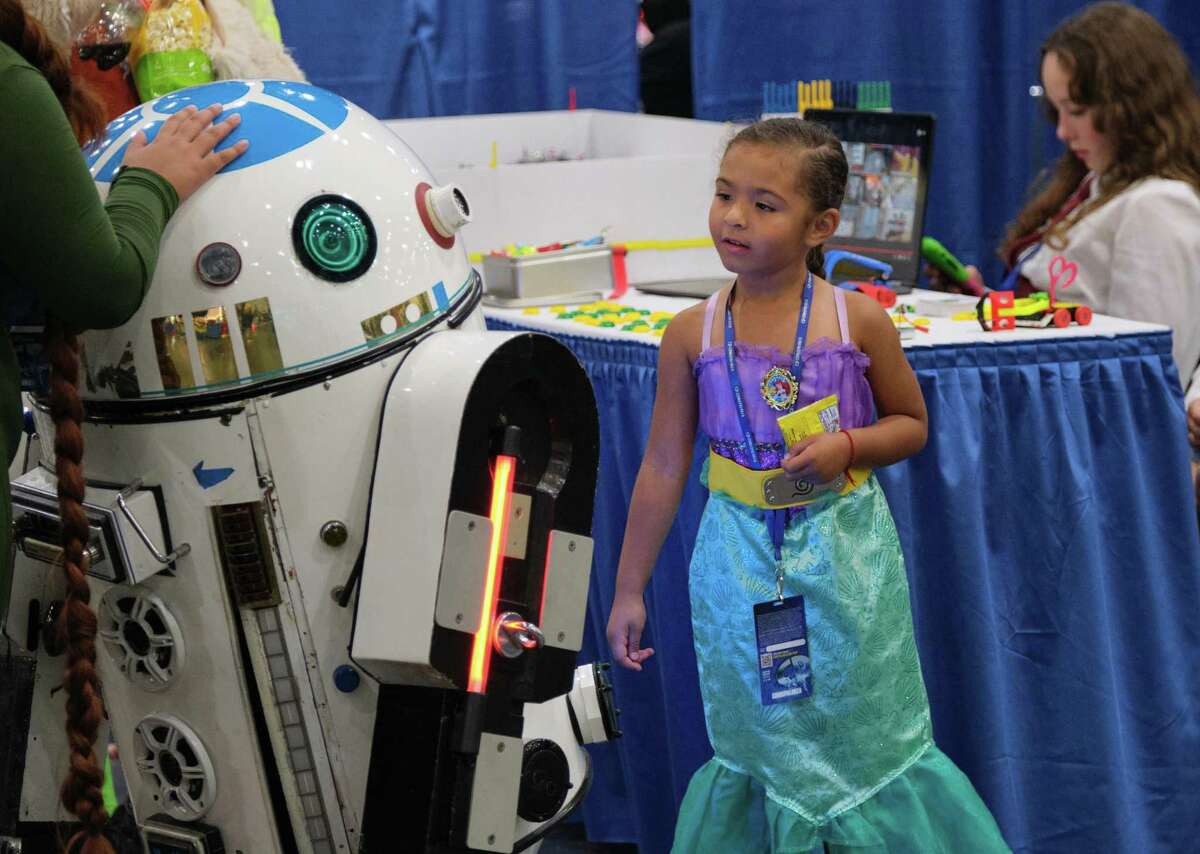 A young Comicpalooza attendee is fascinated with a droid during the Houston Comicpalooza. June 16, 2022