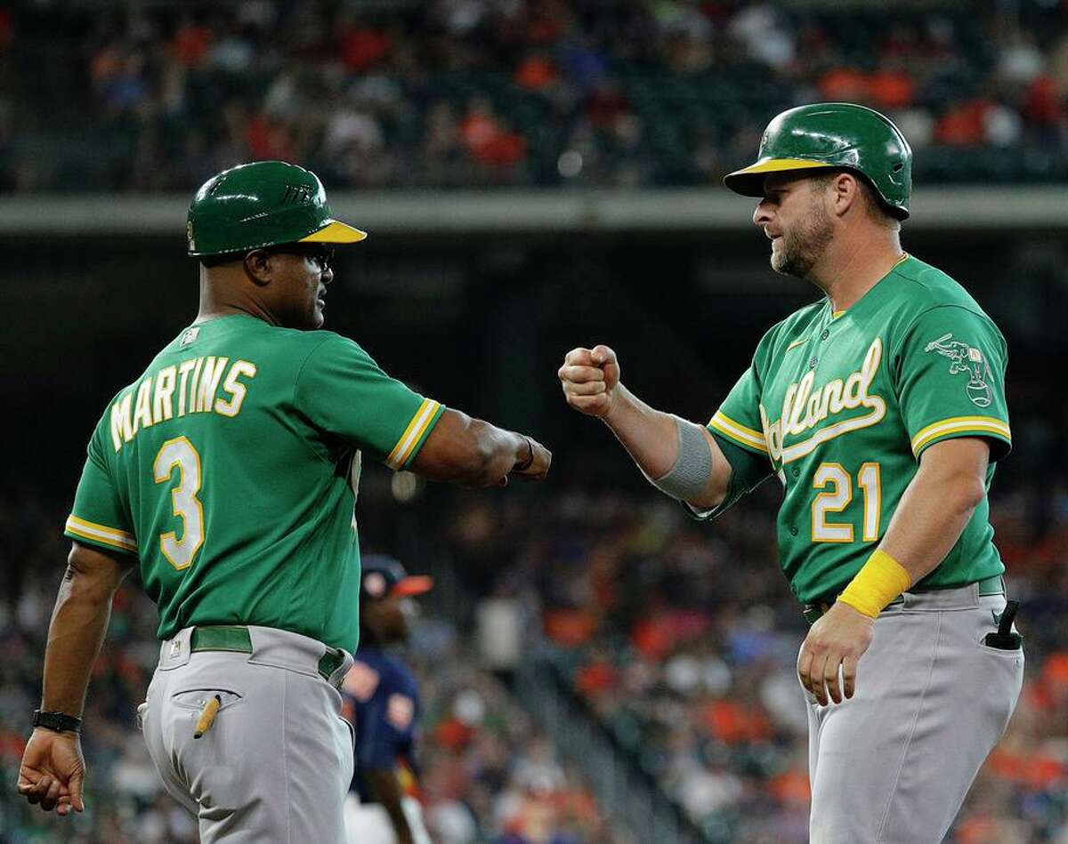 Stephen Vogt fist-bumps coach Eric Martins after singling in a run in the eighth inning at Minute Maid Park.