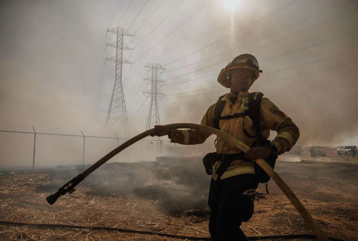 A Contra Costa firefighter battles the Marsh Fire in Pittsburg on July 9. After seven weeks of failed efforts to stop the blaze, firefighters are now trying to douse the flames by flooding the zone with a huge amount of water.