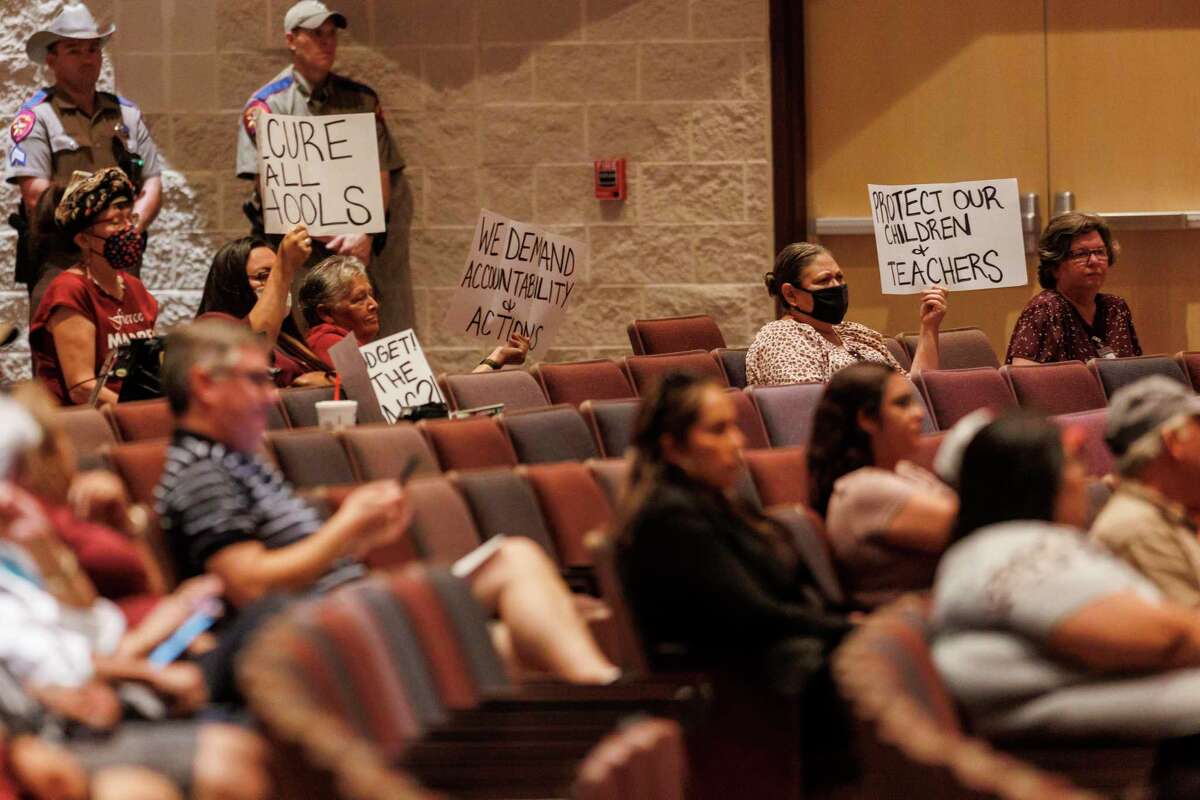 Community members hold up signs as they attend a special meeting of the Uvalde school board Monday. A Texas House report that was harshly critical of both the school district’s security preparations and the police response to the May 24 mass shooting at Robb Elementary dominated the talk at the public forum.
