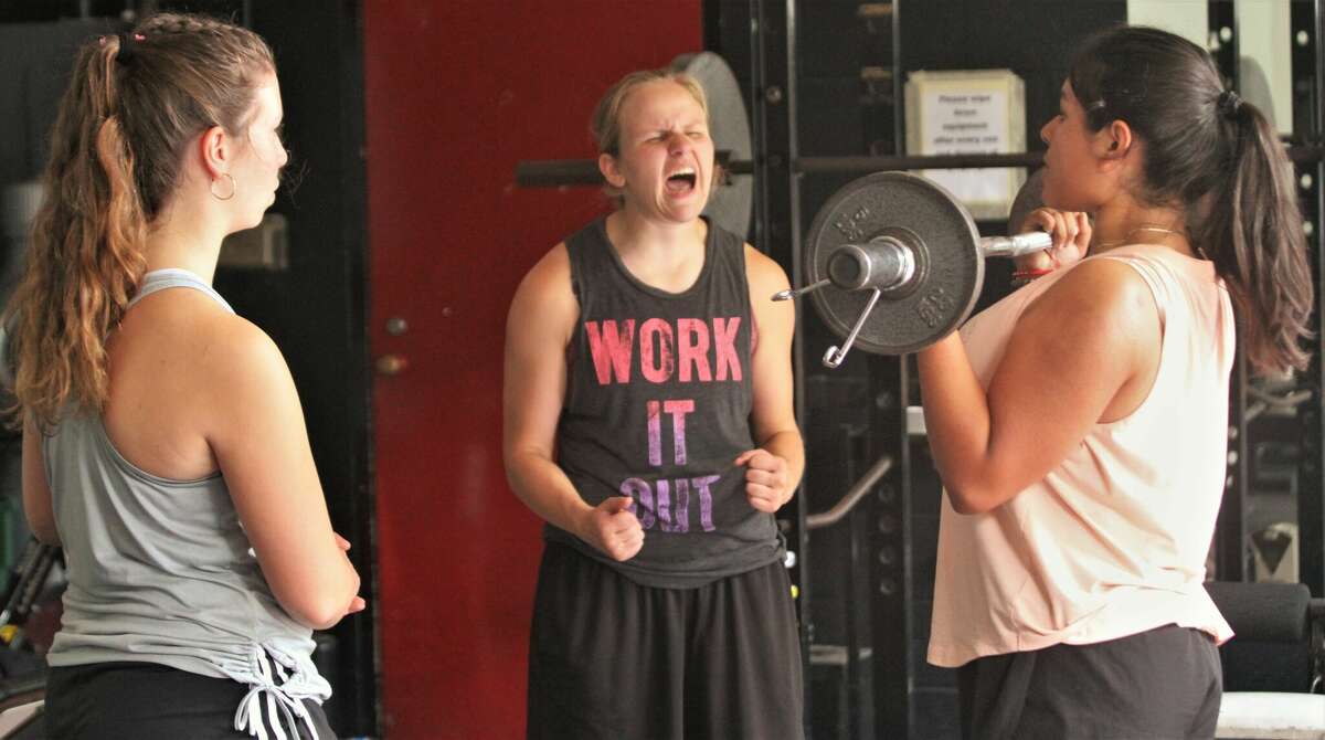 Bear Lake senior Taylor Merrill (center) encourages Conzuelo Magana Garcia to crank out one more rep during a workout on July 15 at Bear Lake High School. 