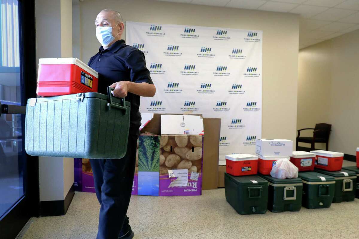 A volunteer carries out warmers and coolers, with food and drinks, from the lobby to deliver to home-bound elderly clients at Meals on Wheels of Montgomery County Tuesday, Jul. 19, 2022 in Conroe, TX.