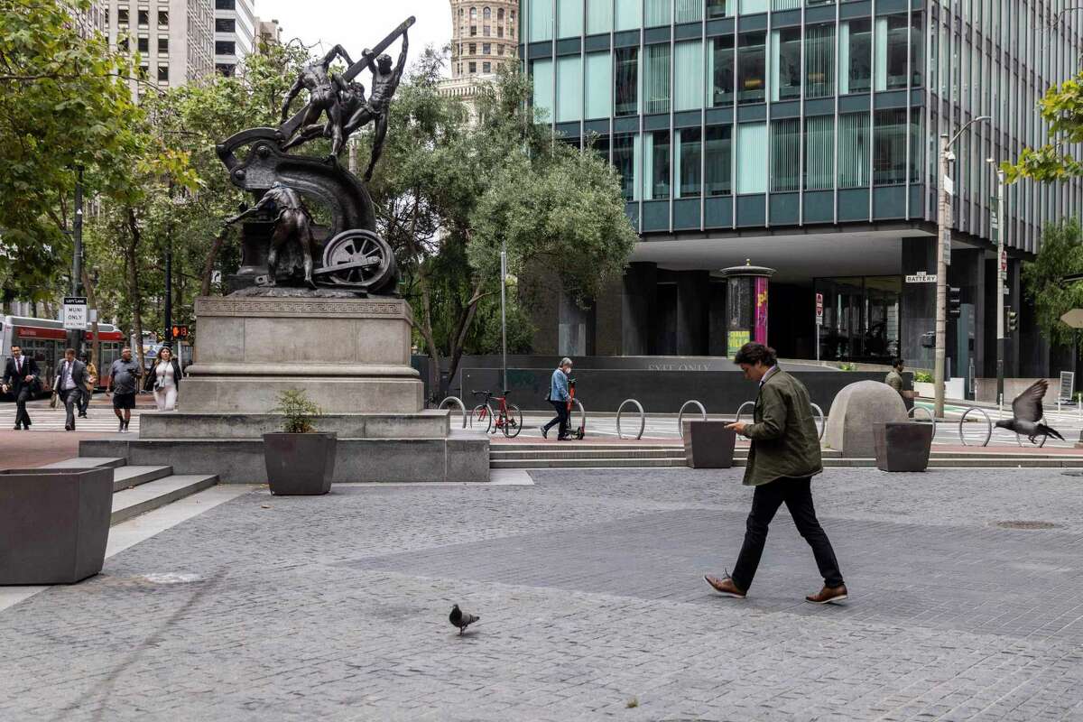 A man walks past pigeons in an empty Mechanics Plaza along Market Street near Battery Street in San Francisco.