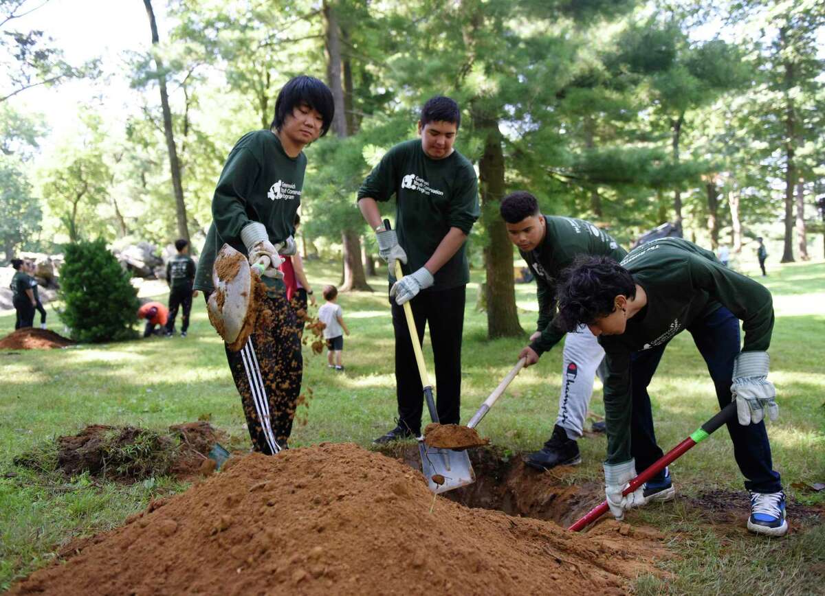 From left, Greenwich Youth Conservation Program workers Yosuke Taki, 15, Bryan Renderos, 14, Abel Perez, 15, and Iggy Krupa, 15, plant a tree at Bruce Park in Greenwich, Conn. Tuesday, July 19 2022. The group planted several trees and then threw a party to celebrate the 112 local teens working summer jobs through the program.