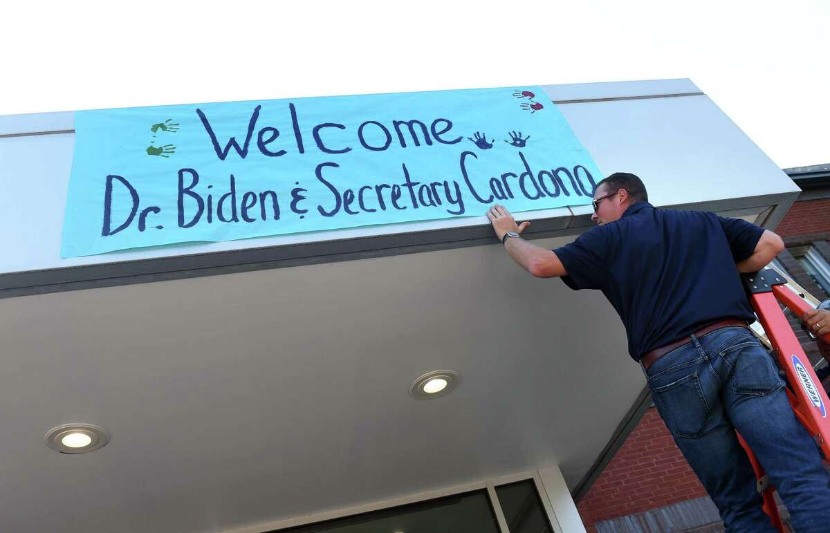 Chris Malizia of the Albertus Magnus Facilities Department secures a sign welcoming First Lady Jill Biden and Secretary of Education Miguel Cardona to the Tagliatela Academic Center at Albertus Magnus College in New Haven on Wednesday.