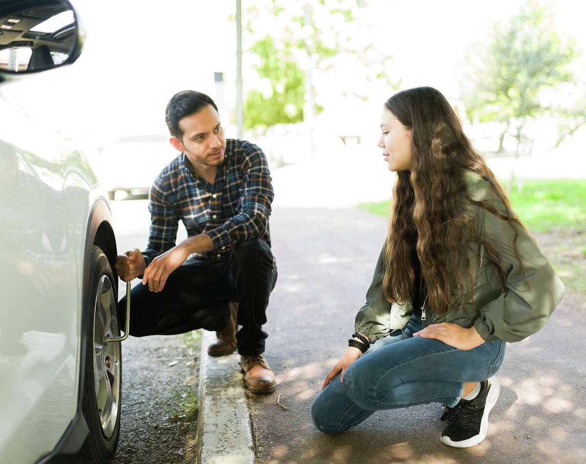 Man teaches daughter how to change a flat tire