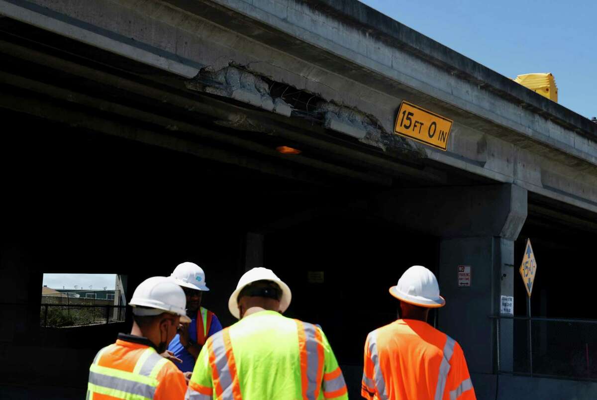 CalTrans workers survey a chunk of concrete missing from the I-80 overpass above Gilman Street in Berkeley, Calif. Wednesday, July 20, 2022. A semi-truck’s cargo collided with the overpass, causing significant damage. The driver fled the scene and police are still searching for them.