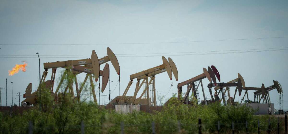 Pumpjacks operate as a flare burns a few hundred yards from apartments Thursday, July 7, 2022, in Midland.