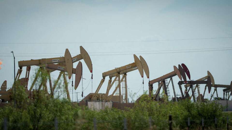 Pumpjacks operate as a flare burns a few hundred yards from apartments Thursday, July 7, 2022, in Midland.