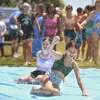 Campers takes turns on the slip and slide at the Norwalk Recreation and Parks Play and Learn summer camp at Calf Pasture Beach in Norwalk, Conn. on Wednesday, July 20, 2022.