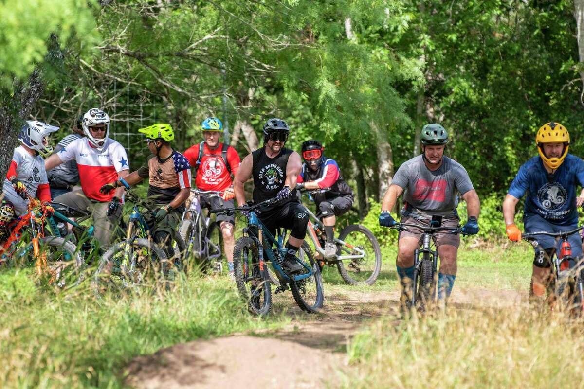 Dirt Therapy Project's founder and president, Jonathan Hagerman, center, is flanked by bike riders during an event at Seguin Mountain Bike Skills Park May 28.