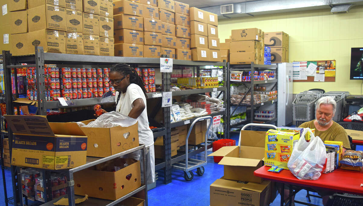 Latasha Hardiman sorts fresh vegetables for clients of the food pantry at The Salvation Army in Jacksonville while fellow volunteer Tony Goodall goes through boxes of donated goods.