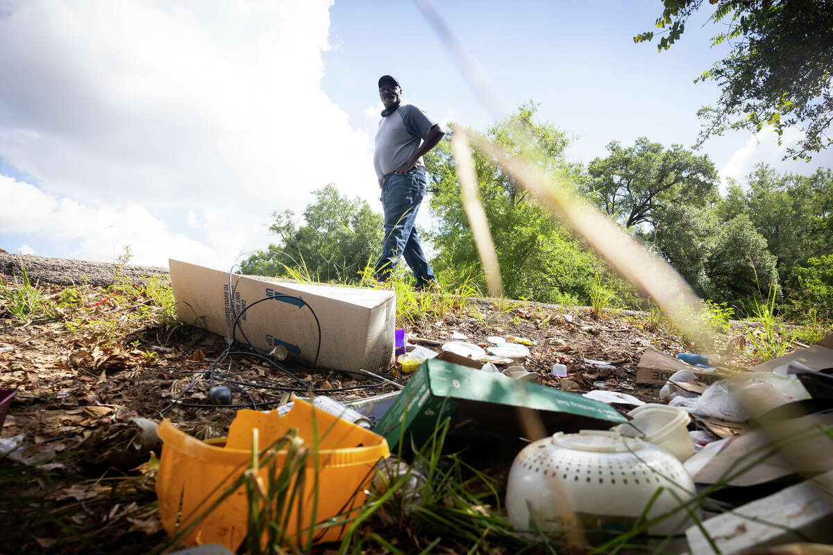 Raymond Dugas surveys the pile of trash left by people across the street from his property northeast of downtown Houston on July 8, 2022. Dugas says people have been using the space for illegal dumping for years.