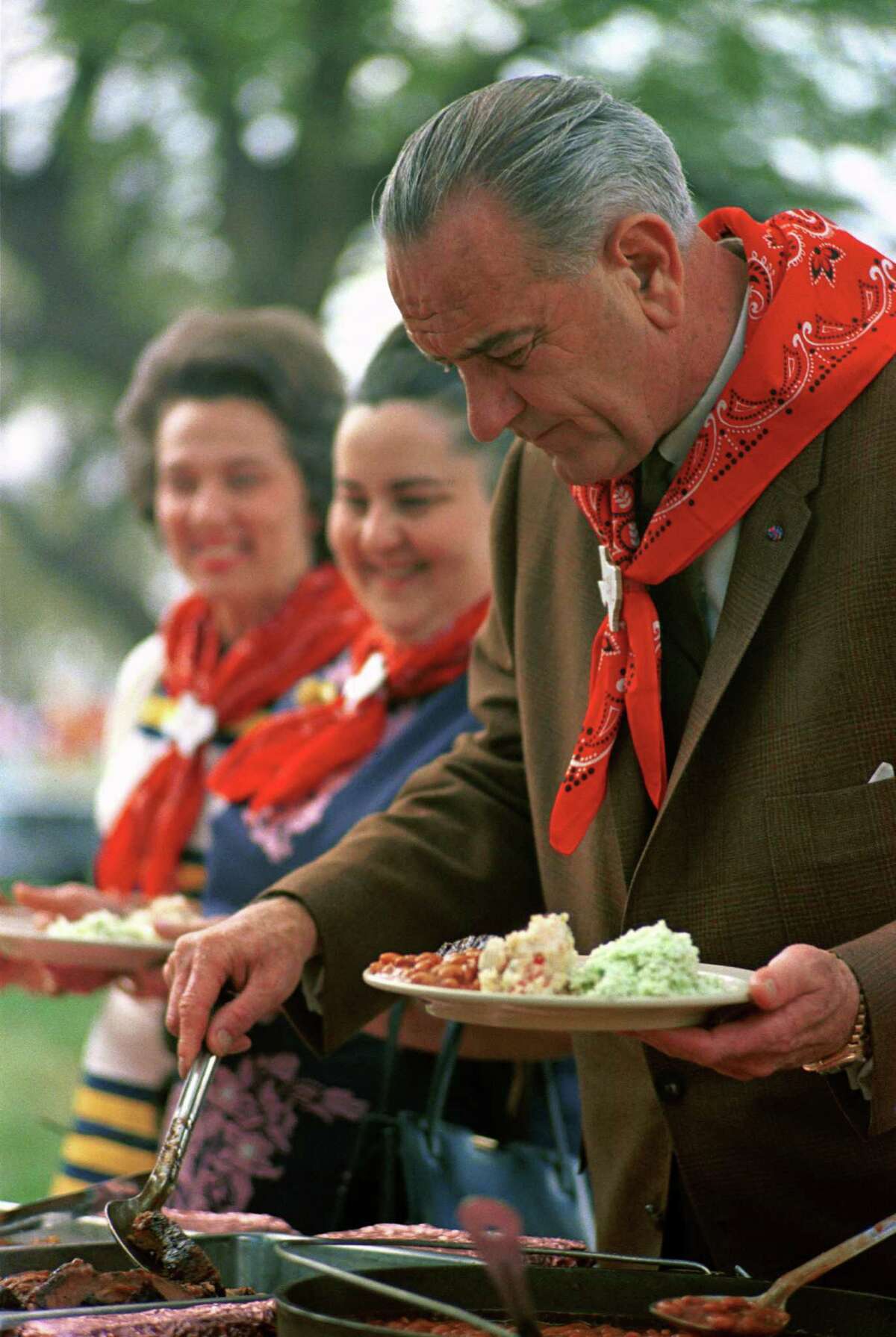 President Lyndon B. Johnson helps himself to barbecue. Next to him in line are Mrs. Guillermo Sevilla-Sacasa and Nellie Connally.