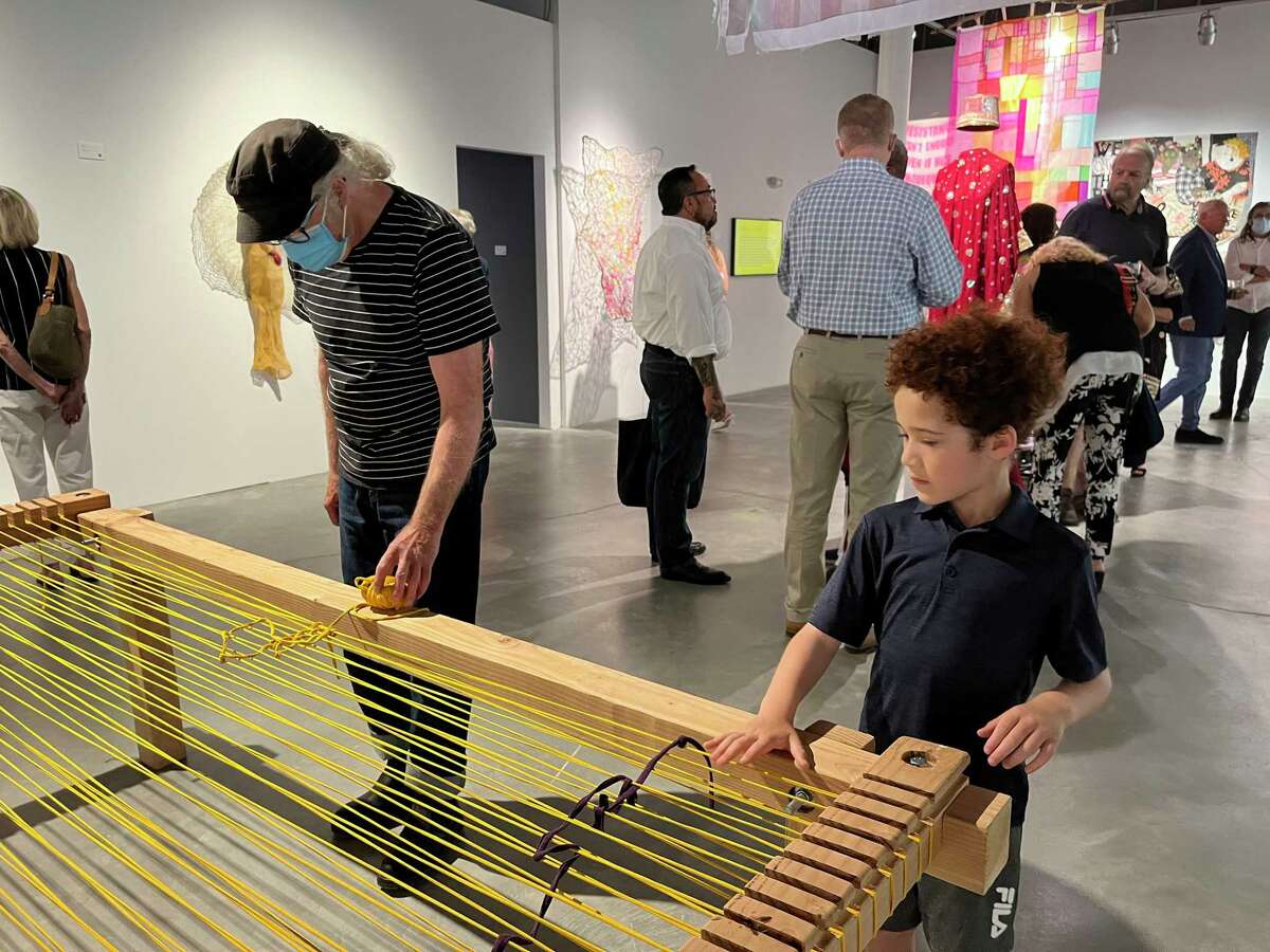 An attendee explores the interactive loom created by Fiber Artists Miami Association.