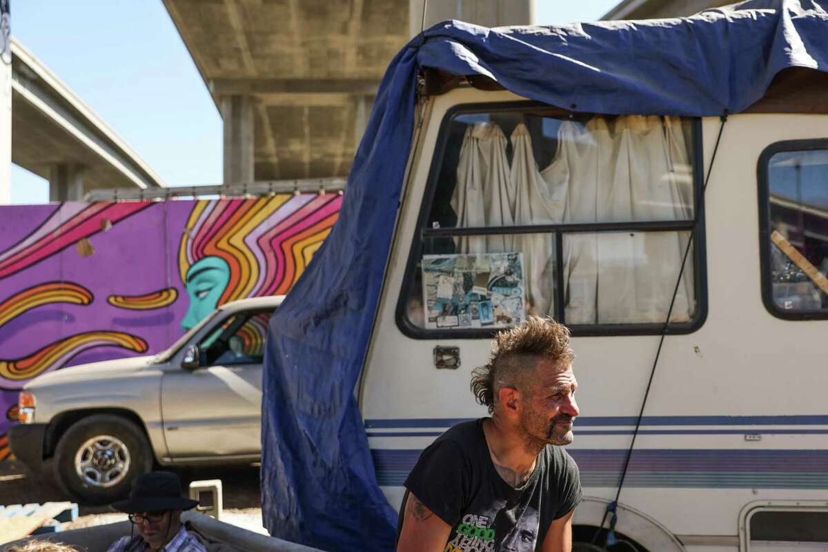 Wood Street resident Jason Faustini listens to a zoom hearing which will decide the future of the encampment in Oakland, Calif., on Friday, July 22, 2022. A judge decided to extend the temporary restraining order against Caltrans which prohibits them from clearing out the encampment,